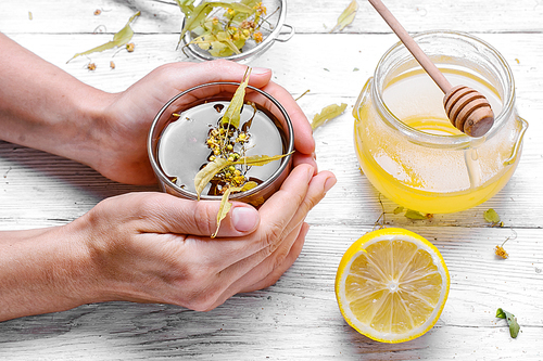 glass of antiviral Linden tea with honey in the hands of women