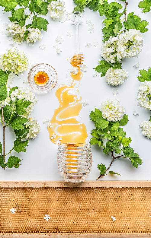 Honey stains from jar  with flowers and honey comb on white background, top view