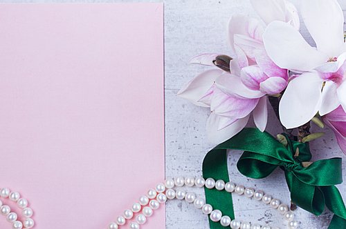 Magnolia flowers and jewellery flat lay composition with copy space on pink paper