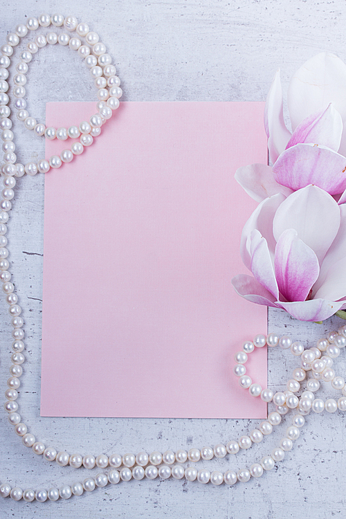 Magnolia flowers and jewellery flat lay composition with copy space on pink paper background