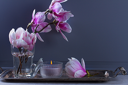 Gray room interior decor with burning candle and magnolia flowers