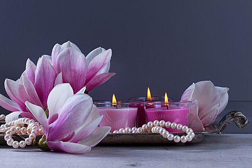 Gray room interior close up decor with burning candle and magnolia flowers