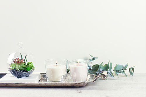 White room interior decor with burning candle and greenery