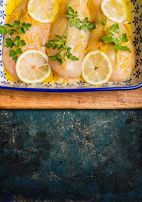 Chicken breast with lemon and seasoning on rustic background, top view, border