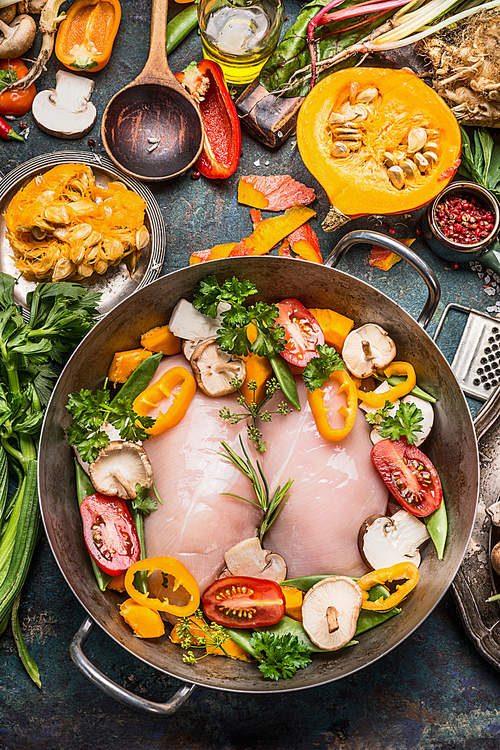 Vegetables autumn dish with chicken breast and pumpkin  with cooking ingredients on dark rustic background, top view