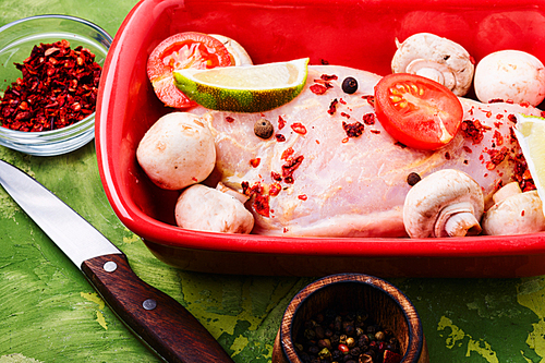 Raw chicken meat with mushrooms in a baking dish