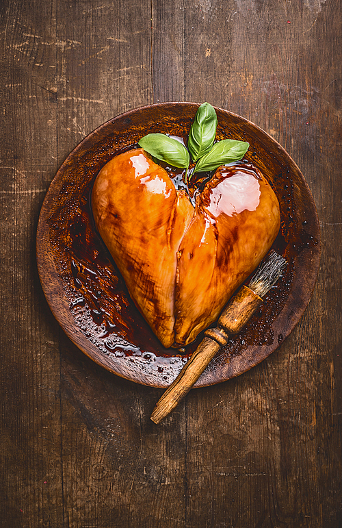 Chicken breast meat in heart shape on wooden plate , top view. Marinated delicious chicken breast fillet for cooking or grill on rustic country table background. Best protein fitness and diet food