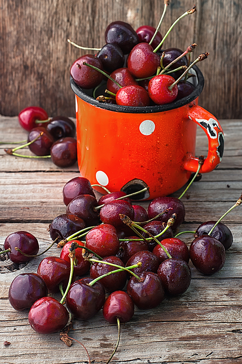 Ripe cherries on wooden background in the iron circle