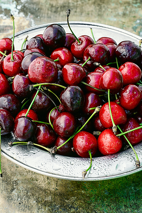 Ripe fruit of sweet cherry in the iron plate on metal background