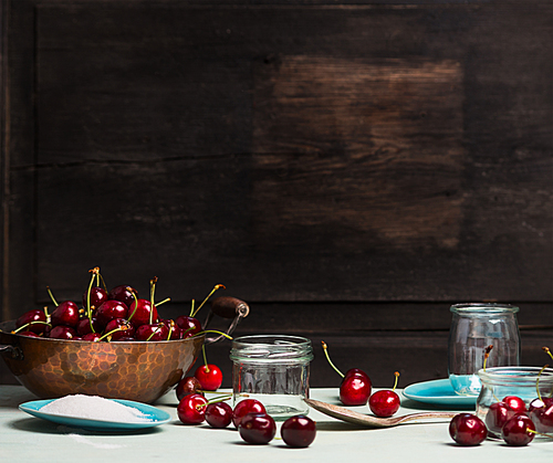 Sweet cherry jam and  jelly preserve preparing on rustic wooden background, place for text, kitchen scene