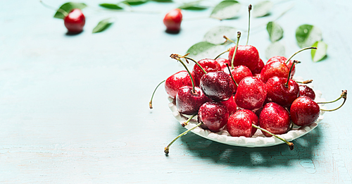 Bowl with fresh red cherry berries on light blue background, front view. Summer fruit concept