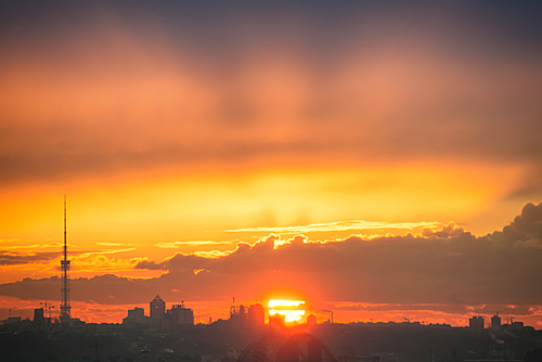 Sunset in the city with silhouette of buildings and sun on orange sky. Kiev, Ukraine