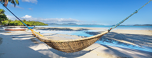 Tropical paradise beach with palm trees and traditional braided hammock