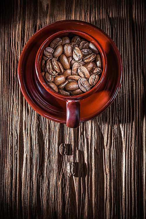 Coffee beans cup saucer on vintage wooden board.