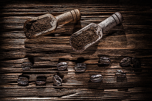 Ground coffee beans in scoop on vintage wooden board.