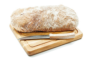 loaf of bread on carving board with kitchen knife isolated