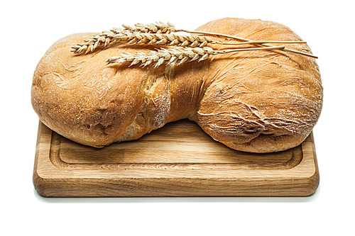 sweet bread on carving board and wheat ears isolated white