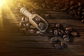 Coffee beans in scoop on vintage wooden board.
