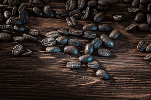 Heap of coffee beans on wooden board.