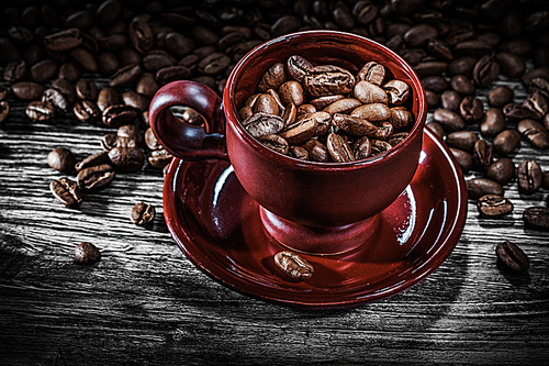 Coffee grains cup saucer on wooden board.