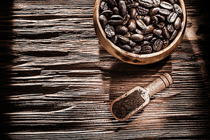 Ground coffee beans bowl scoop on vintage wooden board.