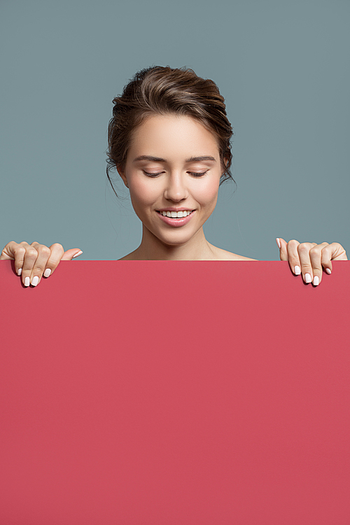Attractive smiling woman holding red empty paper blank in her hands
