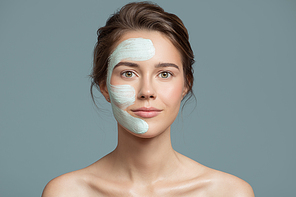 Portrait of beautiful woman with blue cream mask on her face.