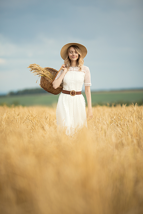 Young attractive woman and golden wheat field. Harvest concept.