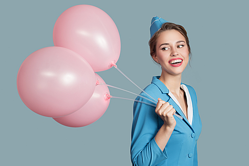 Happy smiling stewardess with pink balloons on blue background.