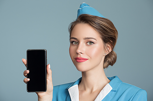 Attractive stewardess holding smartphone with empty screen in hand.