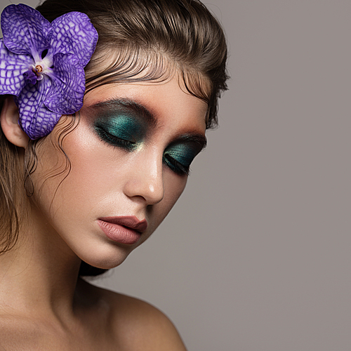 Fashion portrait of beautiful woman with bright make up and orchid near face.