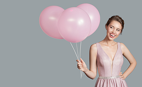 Portrait of smiling woman. Holding pink balloons in her hand. Blue background.