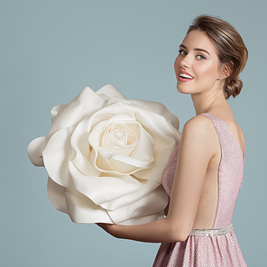 Beautiful charming woman holding giant white rose in her hands.