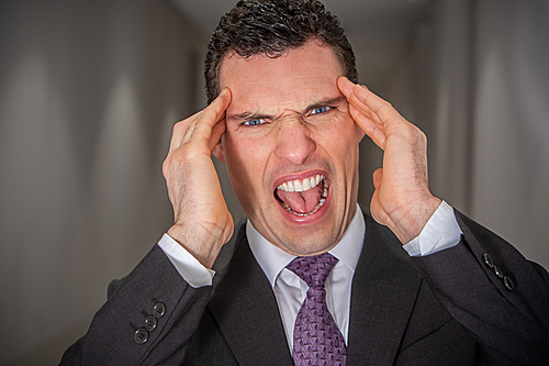 Stressed, shouting, screaming, depressed angry businessman holding his head in pain and anger from stressful migraine headache or mental health crisis