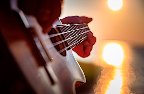 Woman at sunset playing the ukulele