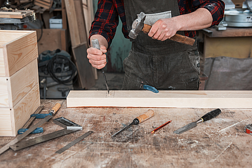 The worker makes measurements of a wooden board with ruler.