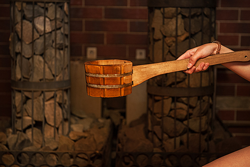 Wooden bath accessories with aromatic oil bottle for bath in the sauna and woman on background