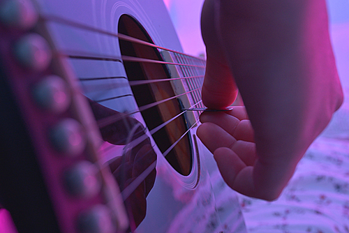 Acoustic guitar played by a girl and colorful lights