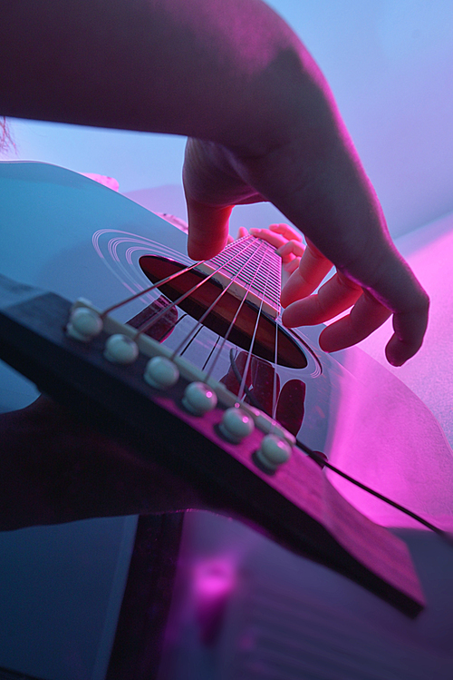 Acoustic guitar played by a girl and colorful lights