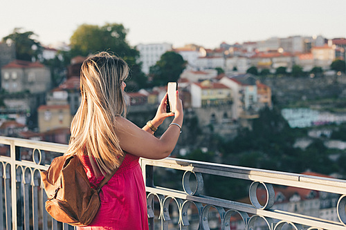 Young woman tourist enjoying beautiful landscape view on the old town with river and famous iron bridge during the sunset in Porto city, Portugal