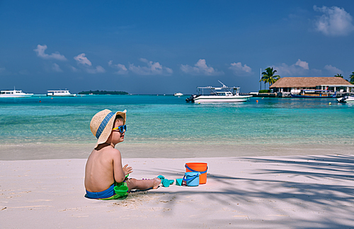 Three year old toddler boy playing with beach toys on beach.  Summer family vacation at Maldives.