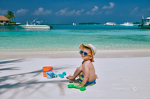 Three year old toddler boy playing with beach toys on beach.  Summer family vacation at Maldives.