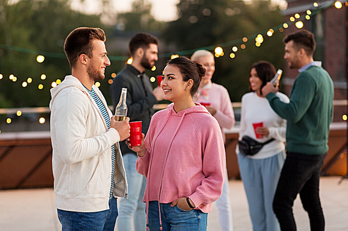 leisure, celebration and people concept - happy friends with drinks in party cups toasting at rooftop