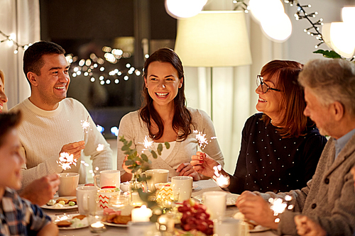 celebration, holidays and people concept - happy family with sparklers having tea party at home