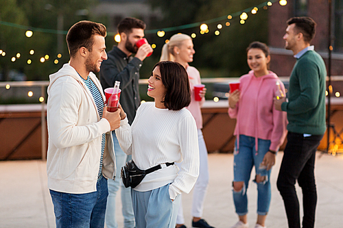 leisure, celebration and people concept - happy friends clinking drinks in party cups toasting at rooftop