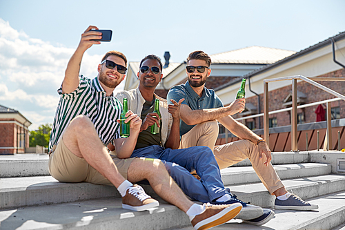 leisure, technology and people concept - happy male friends taking selfie by smartphone and drinking beer on street in summer