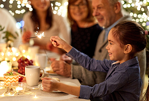 celebration, holidays and people concept - happy girl with sparkler at family tea party