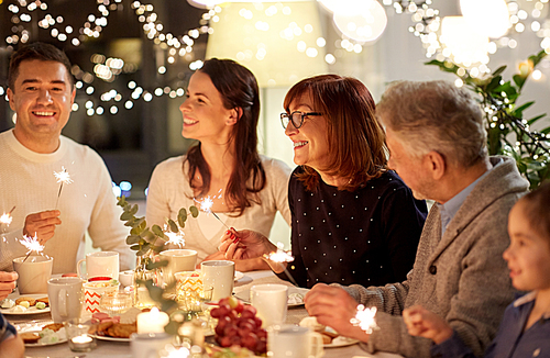 celebration, holidays and people concept - happy family with sparklers having tea party at home