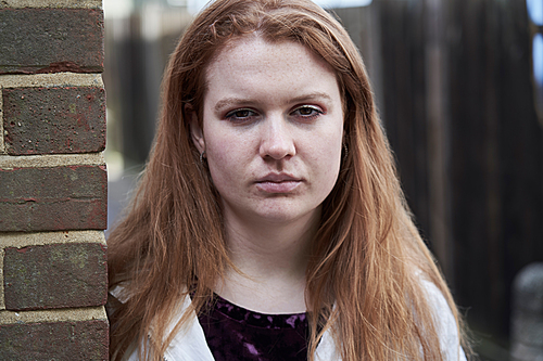 Portrait Of Serious Teenage Girl Leaning Against Wall In Urban Setting