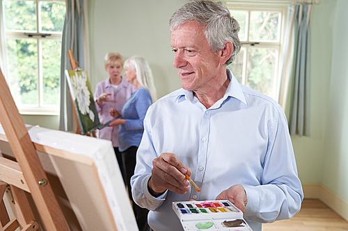 Senior Man Attending Painting Class With Teacher In Background